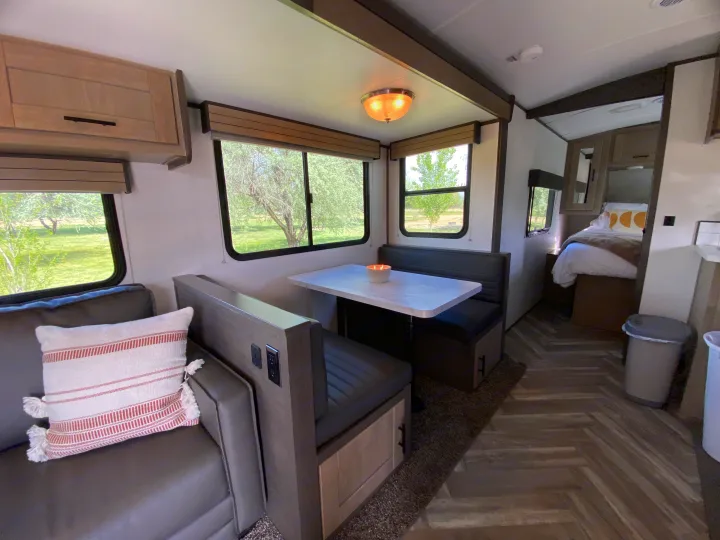 Modern RV rental interior, showcasing a cozy living area, dining nook with table, and a glimpse of the bedroom. Ideal for travelers.. Cruiser RV M-277BHS 2021