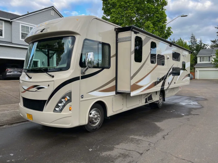 Full view of a spacious beige Class A motorhome, an ACE model, parked on a street. Great for an RV rental vacation!. Thor A.C.E. 2017