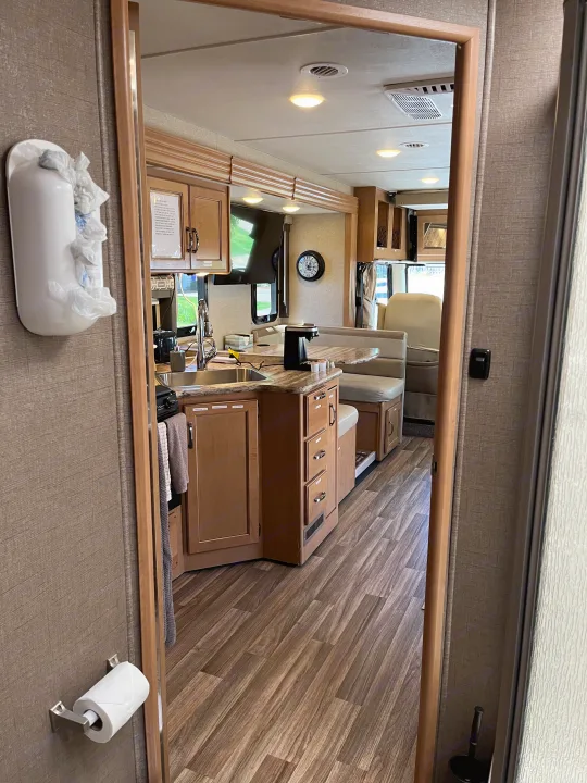 RV rental: Mirror view of a bright and inviting interior, featuring a kitchen, cozy dinette, and wood-look floor.. Thor A.C.E. 2017