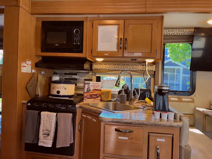 RV rental kitchen featuring a microwave, stove, sink, coffee maker, and organized cabinets for a comfortable stay.. Thor A.C.E. 2017