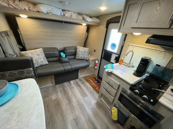 Cozy RV rental interior with convertible sofa, compact kitchen, and bunk bed for comfortable travel.. Coachmen Catalina Summit Series 7 2022