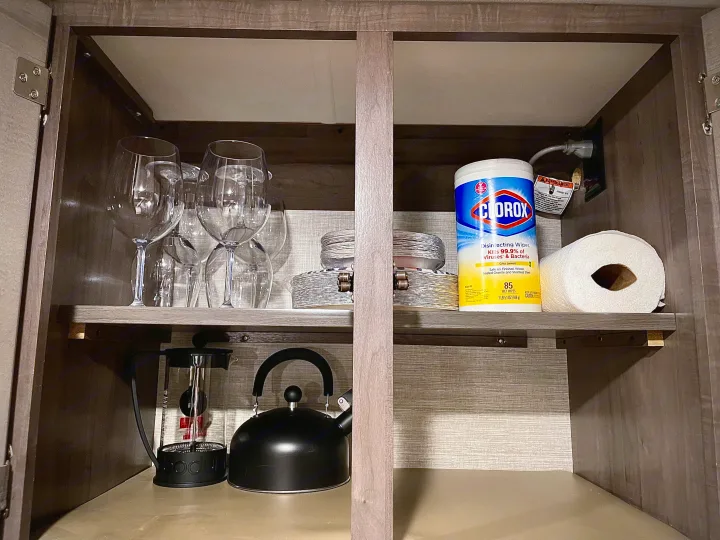RV rental cabinet stocked with kitchen essentials: wine glasses, kettle, French press, wipes, & paper towels.. Winnebago Minnie Winnie 2020
