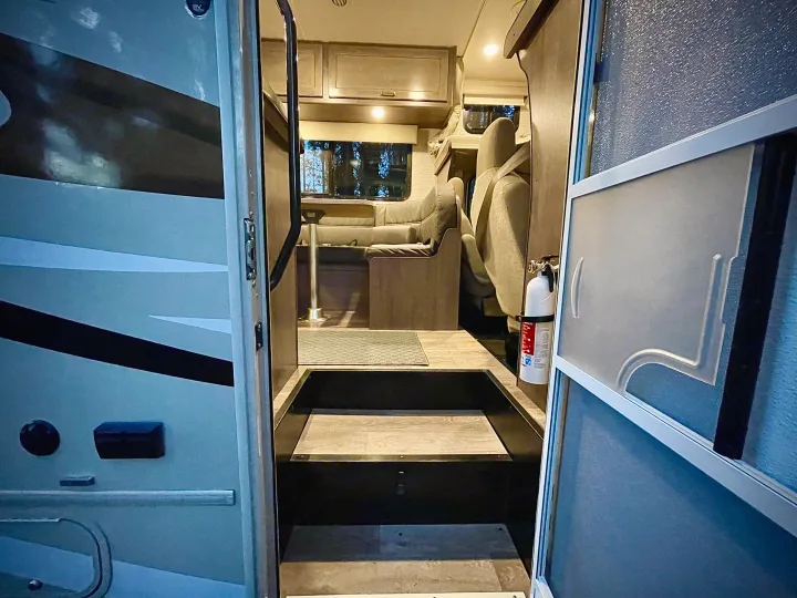 This RV rental's inviting interior features steps, a dinette, seating, and a fire extinguisher, ready for your next adventure.. Winnebago Minnie Winnie 2020