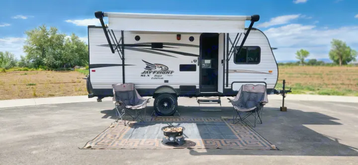 RV rental ready for fun! Jay Flight travel trailer with awning, chairs, rug, and fire pit set up for outdoor comfort.. Jayco Jay Flight SLX 2016