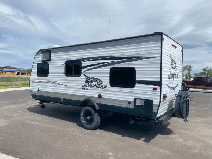 White & gray Jayco Jay Flight SLX travel trailer, ideal for an RV rental, parked on asphalt under cloudy skies.. Jayco Jay Flight SLX 2016