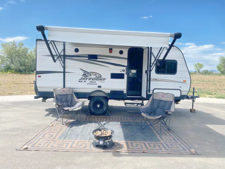 Experience outdoor comfort! This RV rental features an extended awning, chairs, and a fire pit, perfect for a relaxing campsite.. Jayco Jay Flight SLX 2016