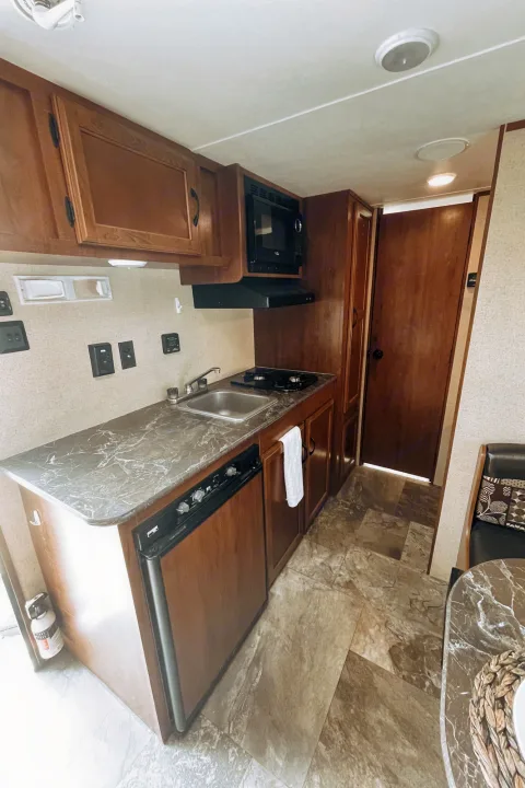 Explore this compact RV rental kitchen, featuring a sink, stove, microwave, and refrigerator, ideal for your next trip.. Jayco Jay Flight SLX 2016