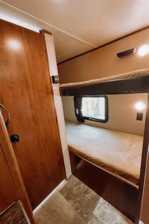 RV rental interior features bunk beds, a window, and a door, providing comfortable camper accommodation.. Jayco Jay Flight SLX 2016