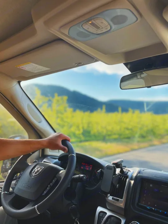 Driving an RV rental on a scenic road trip. Interior view showing steering wheel & mountain views.. Thor Sequence 2021