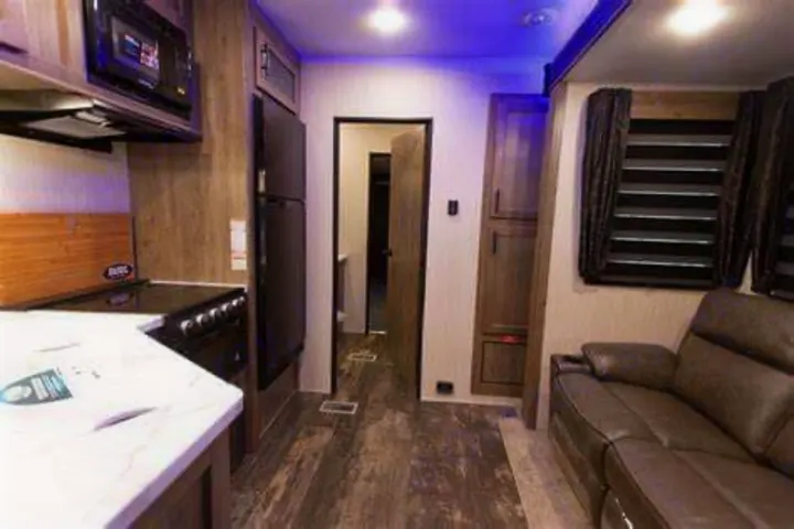 An inviting RV rental interior, complete with a modern kitchen, spacious living area with recliners, and wood floors.. Forest River Cherokee Wolf Pack Toy Hauler 2020