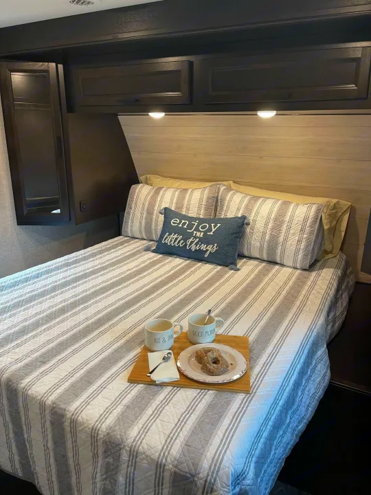 Cozy RV rental bedroom with breakfast in bed and striped bedding. Perfect mobile retreat.. Jayco Eagle HT 312BHOK 2022