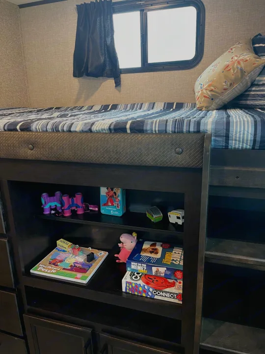 RV rental: cozy bunk bed with striped bedding, decorative pillow, window, and shelves with toys & board games.. Jayco Eagle HT 312BHOK 2022
