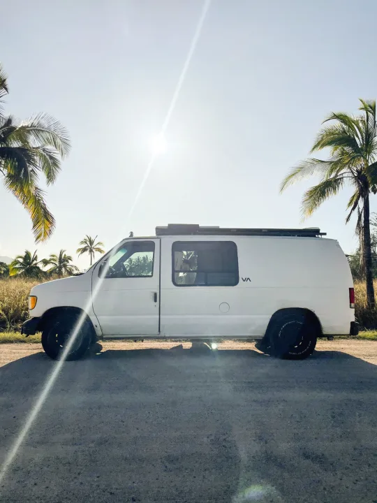 White RV rental van parked on a sunny road with palm trees. Perfect for a tropical adventure.. Ford Econoline 150 2000