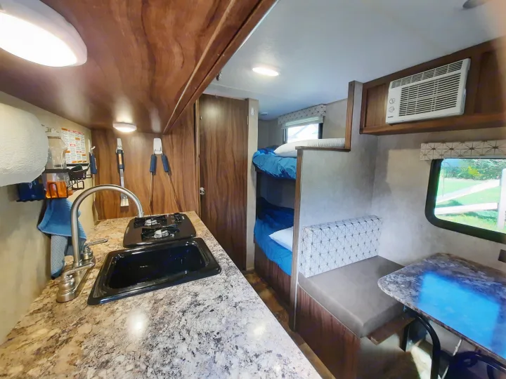 Inside this functional RV rental: a compact kitchen, comfortable bunk beds, cozy dining area, and AC unit.. Forest River Viking Saga 2016