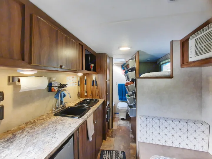 Compact RV rental interior featuring a full kitchen, toilet, cozy bed, and dinette. Ideal for travel.. Forest River Viking Saga 2016