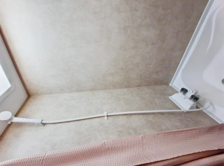 RV rental shower featuring a handheld shower head, controls, and a pink shower curtain in a compact space.. Forest River Viking Saga 2016
