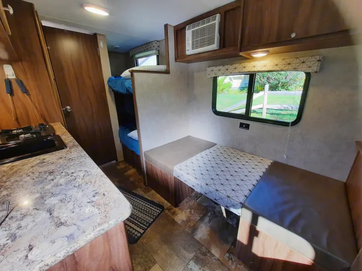Inside a comfortable rv rental: a compact kitchen, private bunk beds, and a dinette next to a window. Ideal for road trips.. Forest River Viking Saga 2016