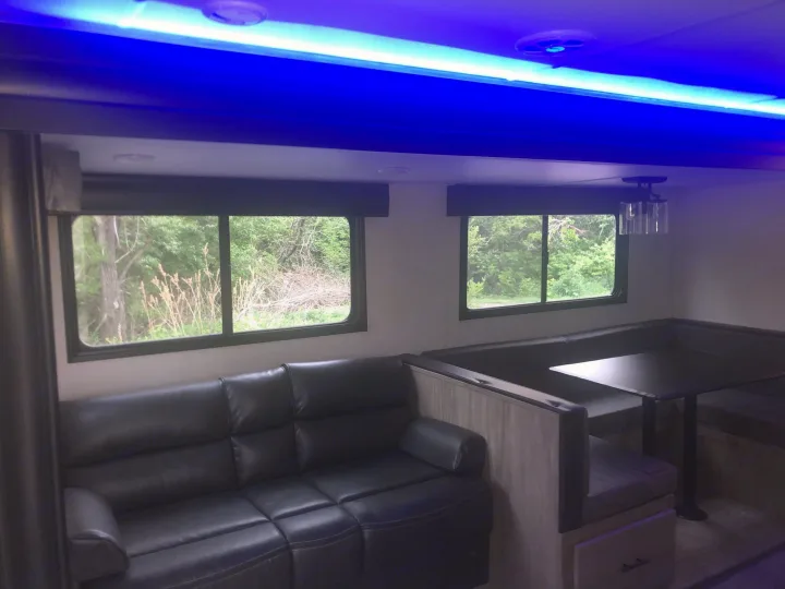 Modern RV rental interior: comfy sofa, dinette, & ambient blue lighting for your next adventure.. Forest River Cherokee Alpha Wolf 2022