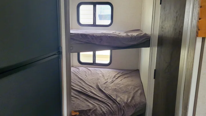 Comfortable bunk beds in an RV rental feature windows, providing a cozy sleeping area.. Forest River EVO 2021