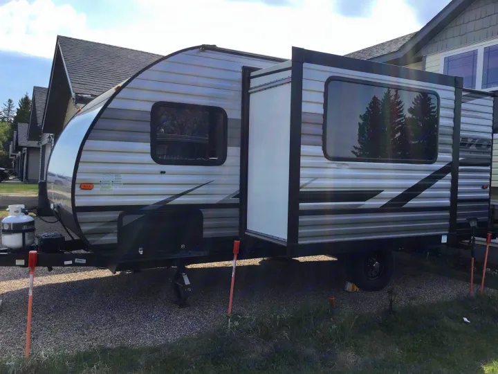 RV rental: Grey travel trailer with slide-out extended, parked on gravel lot near houses.. Forest River EVO 2021