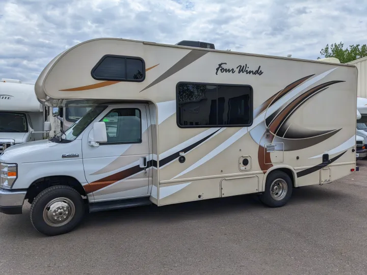 Spacious Four Winds RV rental, a beige Class C motorhome with brown graphics, parked outdoors.. Thor Motor Coach Four Winds 2017