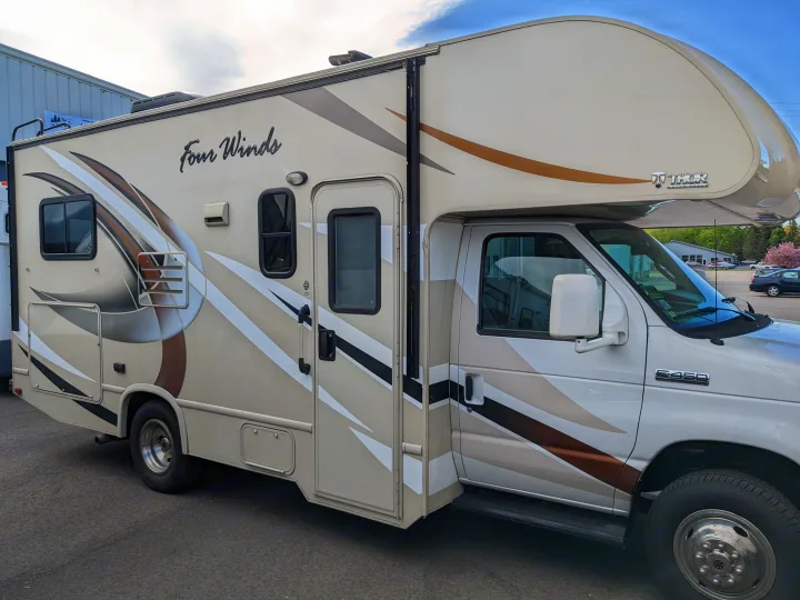 Side view of a white & tan Four Winds Class C RV rental, Thor Motor Coach brand, built on a Ford E-450.. Thor Motor Coach Four Winds 2017