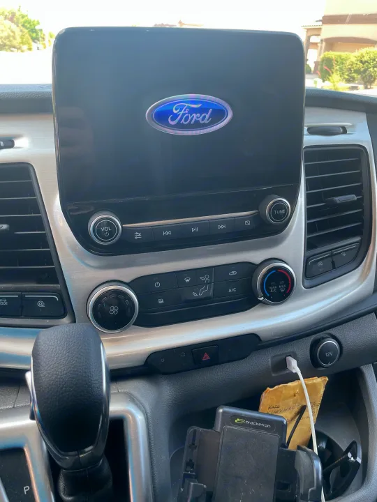 Ford RV rental dashboard interior: touchscreen with Ford logo, media controls, climate panel, gear shifter, and charging ports.. Thor Gemini 2022