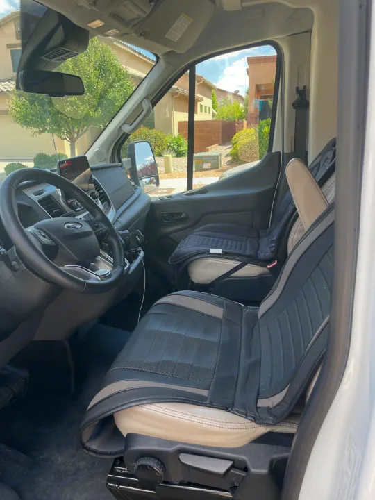 The interior of an RV rental van, showing the driver's cabin, dashboard, and covered front seats.. Thor Gemini 2022
