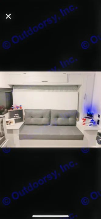 RV rental: Compact gray futon-style couch with light gray overhead cabinets & patriotic decor in a cozy interior.. Forest River Wildwood FSX Platinum 2021