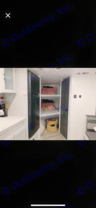 Cozy RV rental interior: kitchen counter, fridge, bunk beds with red pillows, and a basket. Ideal for small families.. Forest River Wildwood FSX Platinum 2021