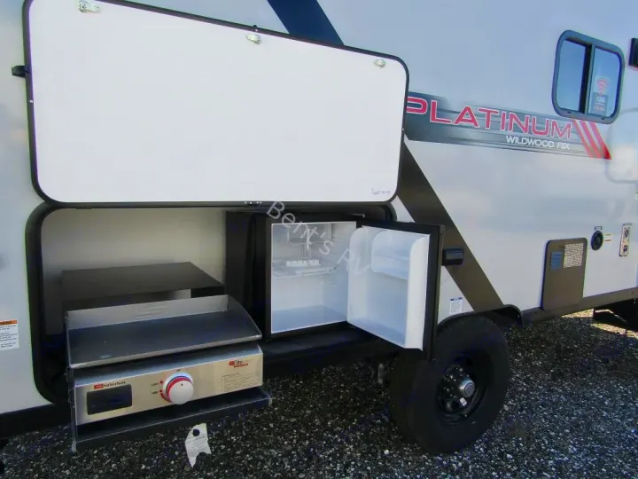 This RV rental features an outdoor kitchen with a Suburban griddle and mini-fridge, perfect for camping.. Forest River Wildwood FSX Platinum 2021