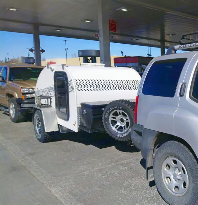 White teardrop trailer towed by a silver SUV at a gas station. Ideal for an rv rental adventure or camping trip.. Little Guy Other 2012