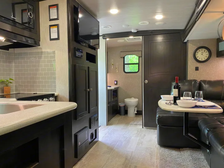 Cozy rv rental interior featuring a modern kitchen, comfortable living area with a set table, and a glimpse of the bathroom.. Heartland RVs North Trail 2019
