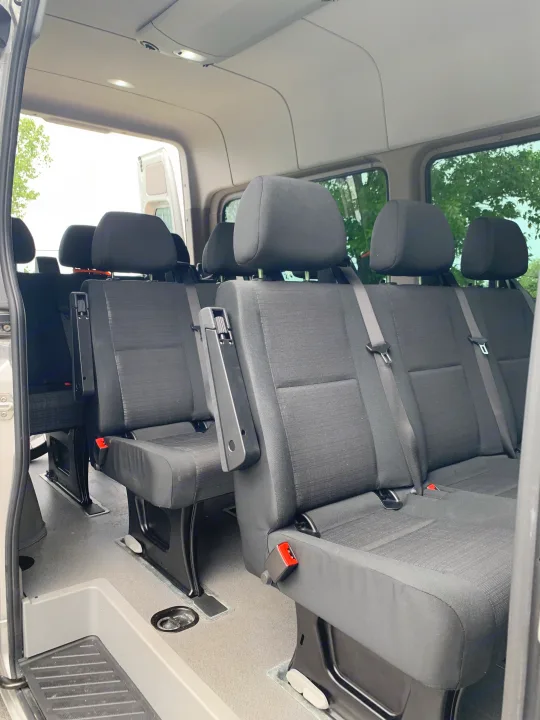 Inside a spacious RV rental, showing multiple rows of black fabric passenger seats with headrests and seatbelts. Ideal for group travel.. Mercedes Benz 2017 Sprinter Van 2017