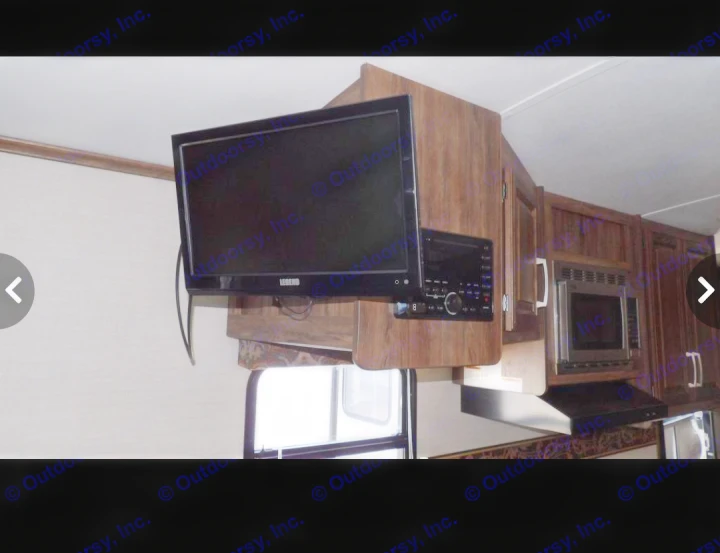 RV rental interior: wall-mounted TV, integrated audio system, microwave, and wooden cabinets for comfort.. Keystone RV Cougar X-Lite 2015