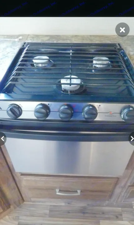 RV rental kitchen: Stainless steel gas stove/oven with 3 burners and control knobs. Ready for cooking!. Keystone RV Cougar X-Lite 2015