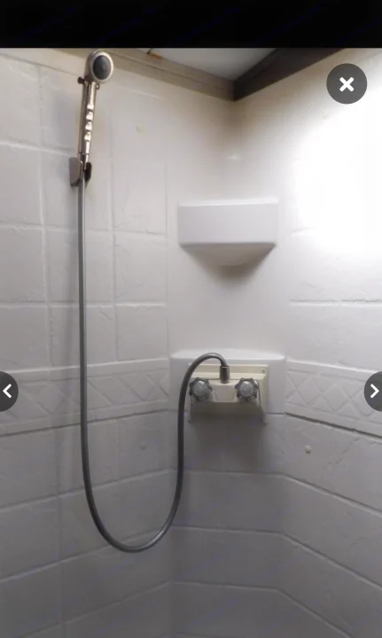 RV rental shower: a compact white shower stall with a handheld showerhead, water controls, and two integrated shelves.. Keystone RV Cougar X-Lite 2015