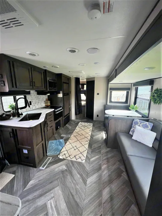 Spacious RV rental interior: modern kitchen, dinette, and living area with stylish grey herringbone flooring.. Highland Ridge Open Range Olympia 2022