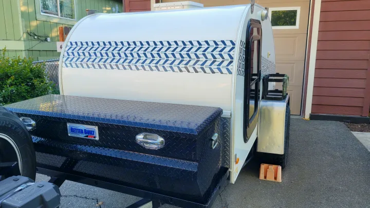 This white teardrop rv rental travel trailer, featuring a unique blue chevron pattern and front storage box, is ready for adventure.. Little Guy Other 2012