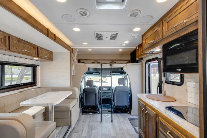 RV rental interior with a dinette, kitchen area, overhead bunk, and front driver's cabin view, showcasing the living space.. Jayco Melbourne 2022