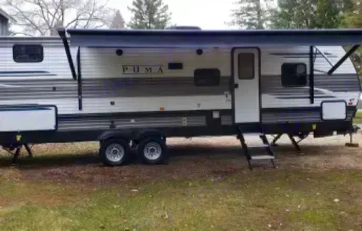 This Puma travel trailer RV rental, parked on grass with its awning extended, offers adventure.. Forest River Palomino Puma XLE Lite 2021
