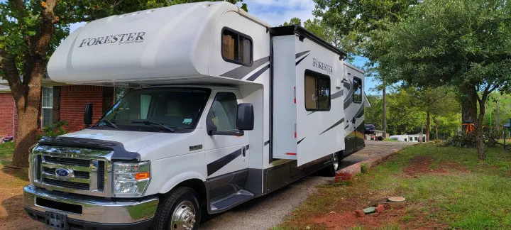 White Forester Class C **rv rental** with extended slide-out, parked on a driveway, ready for your next adventure.. Forest River 3171DS 2016