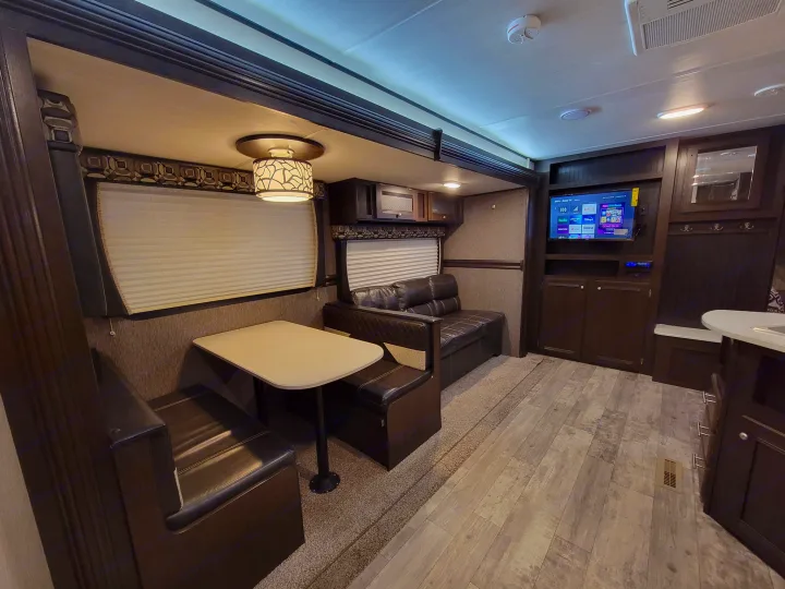 Spacious RV rental interior featuring a comfortable dinette, sofa, and entertainment center in a well-appointed living space.. Heartland RVs Pioneer 2019