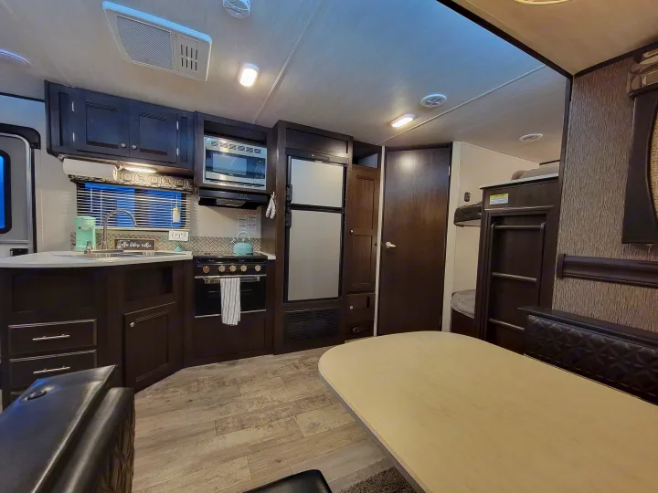 RV rental interior: full kitchen with stove and microwave, dining area, and bunk beds.. Heartland RVs Pioneer 2019