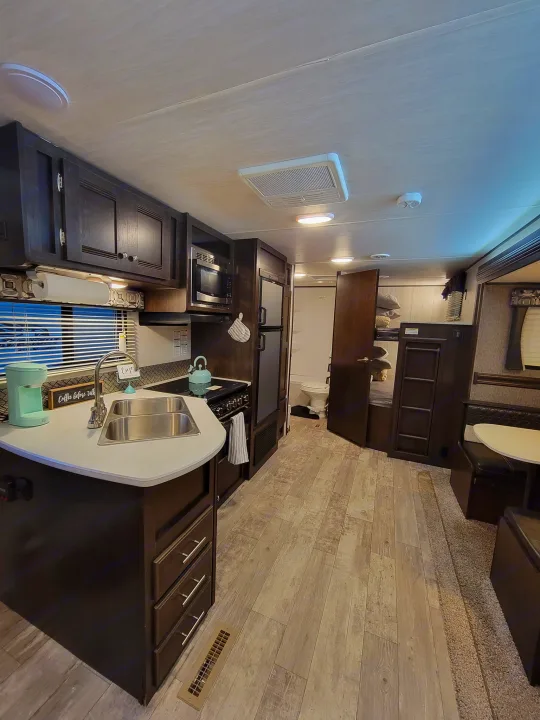 Spacious and modern RV rental interior featuring a full kitchen, living area, and comfortable bunk beds. Perfect for your next adventure.. Heartland RVs Pioneer 2019