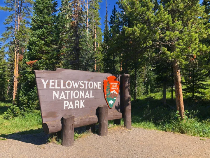 Welcome to Yellowstone National Park! This iconic entrance sign amidst tall trees is your gateway to an amazing RV rental adventure.. Airstream Sport 2019