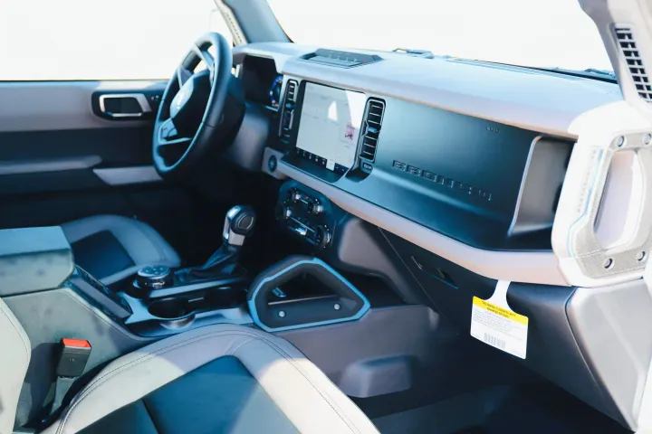 View inside a Ford Bronco, showing the dashboard, touchscreen, steering wheel, and gear shifter. Consider it for your rv rental.. Ford Bronco 2024