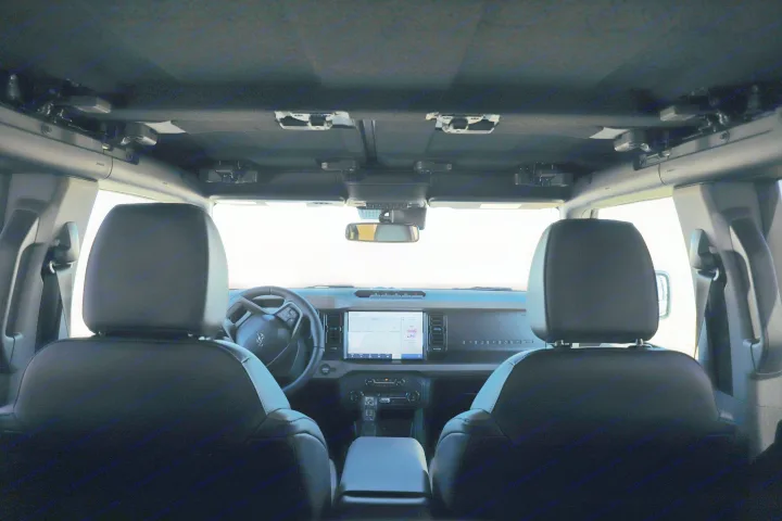 RV rental adventure: Ford Bronco interior from rear seats, featuring dashboard, steering wheel, and roof latches.. Ford Bronco 2024