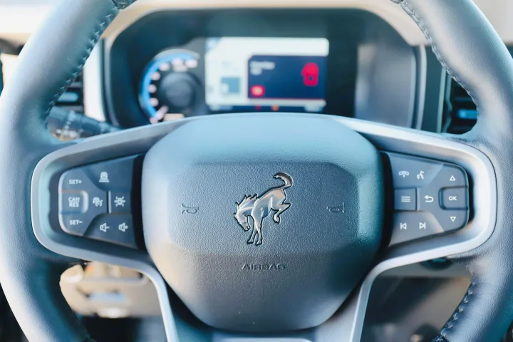 Detailed view of a modern Bronco steering wheel, showing controls and dashboard, perfect for your next rv rental journey.. Ford Bronco 2024
