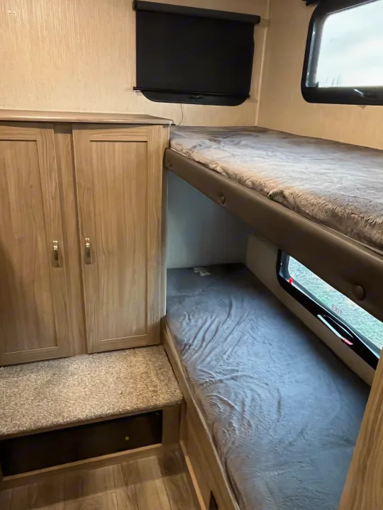 RV rental interior with bunk beds, wardrobe, and window. Comfortable and practical sleeping arrangements for your trip.. Coachmen Freedom 2021
